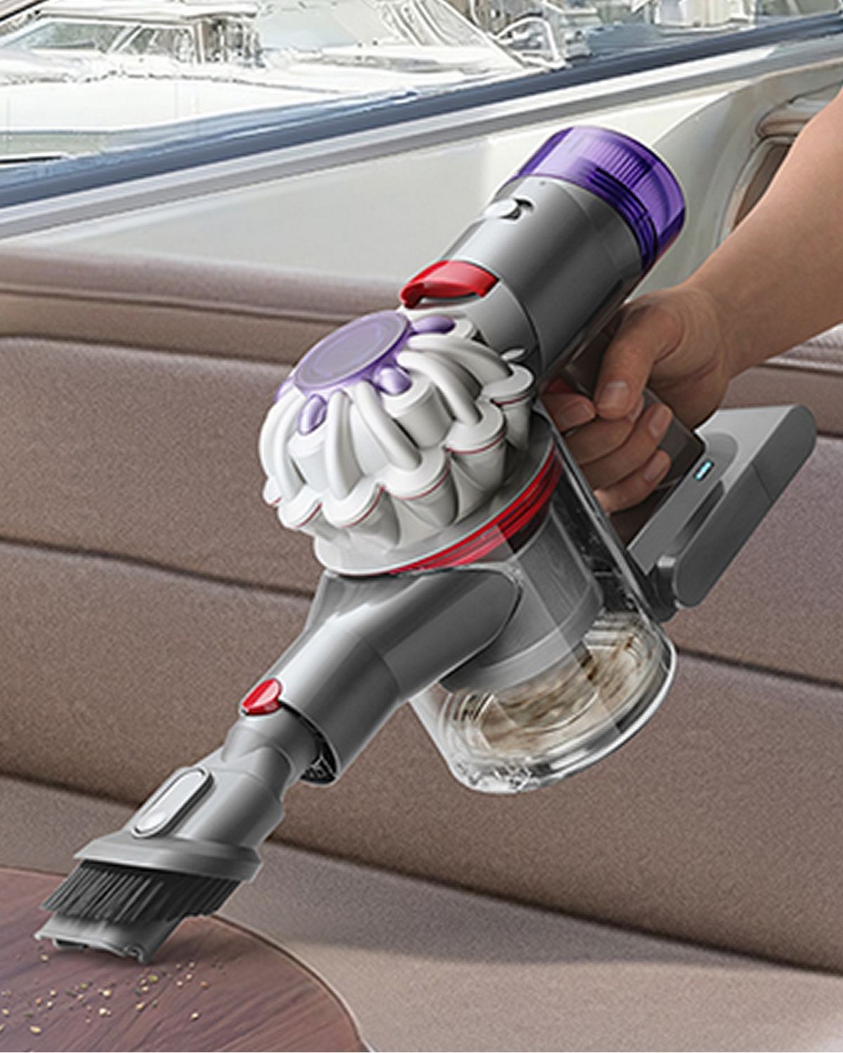 The Dyson Car+Boat handheld vacuum with the Combinationton tool cleaning mess from a table on a boat.